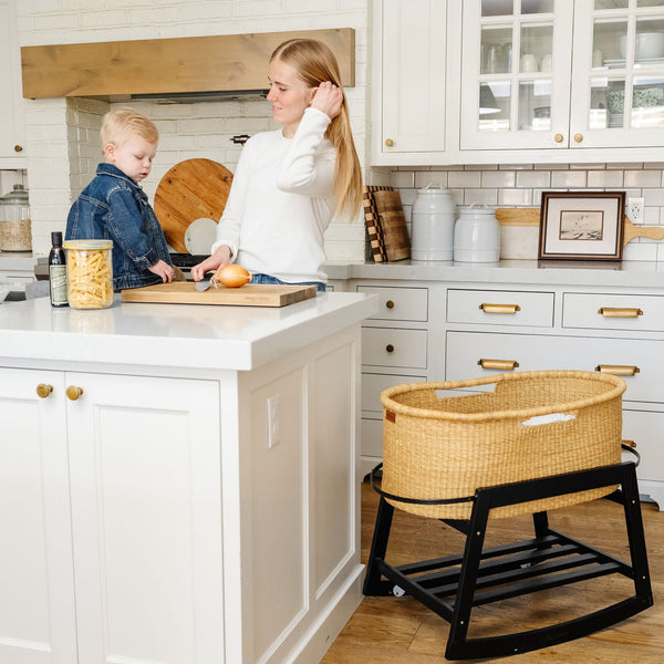 Woman and child in a kitchen with a wicker high chair.